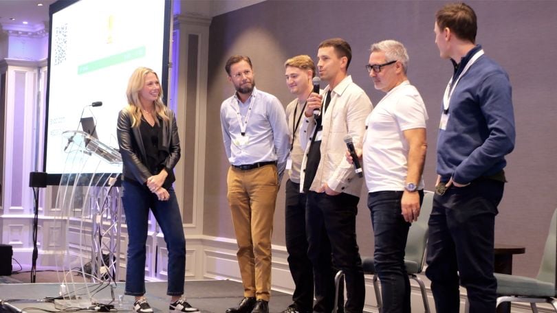 A group of Pluralsight employees stand on a stage in a line for an event. 